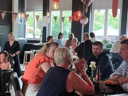 Een feest in de zaal: volle tafels, slingers en ballonnen.